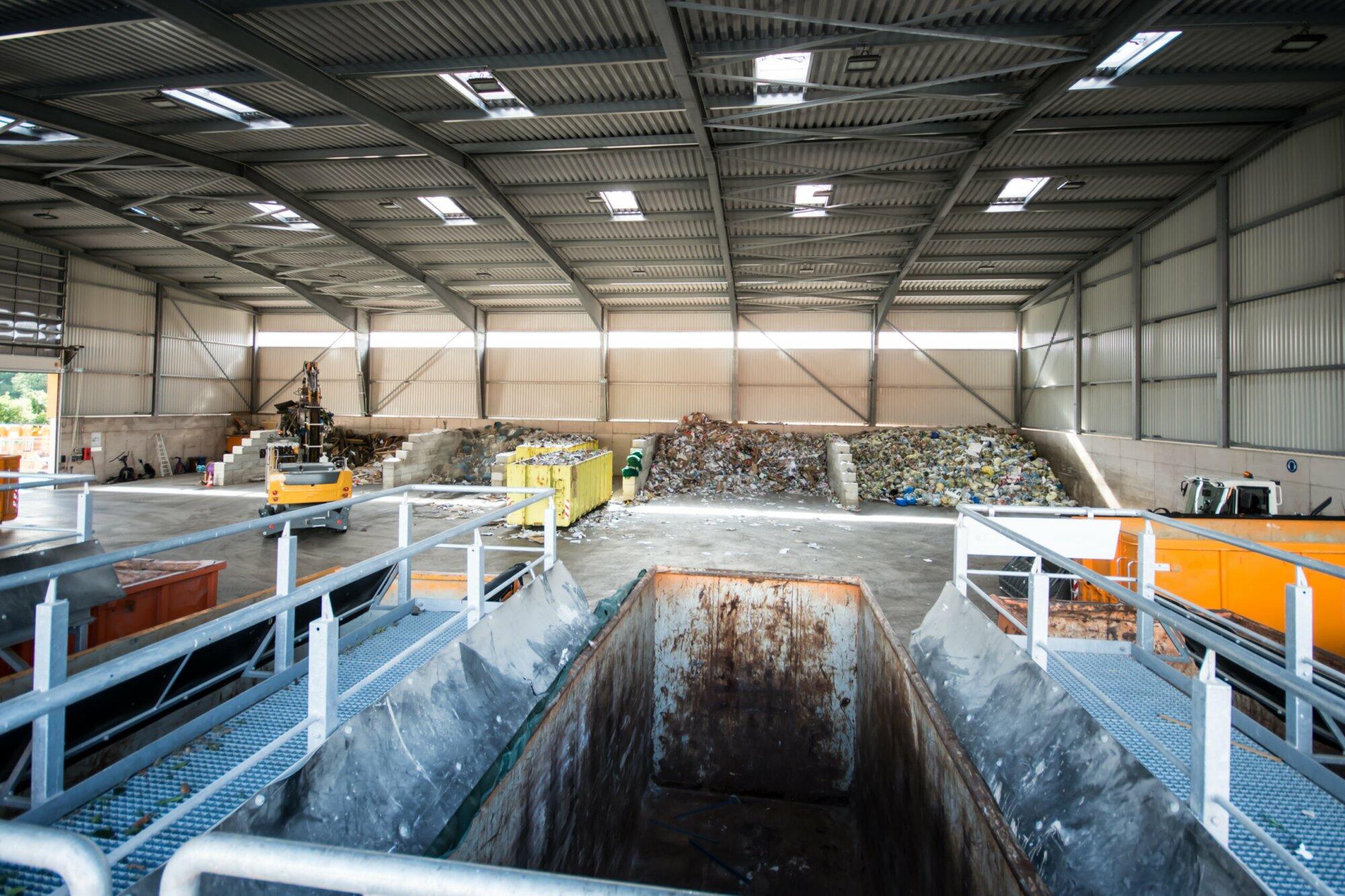 Recyclinghalle mit Müllbergen und Containergrube